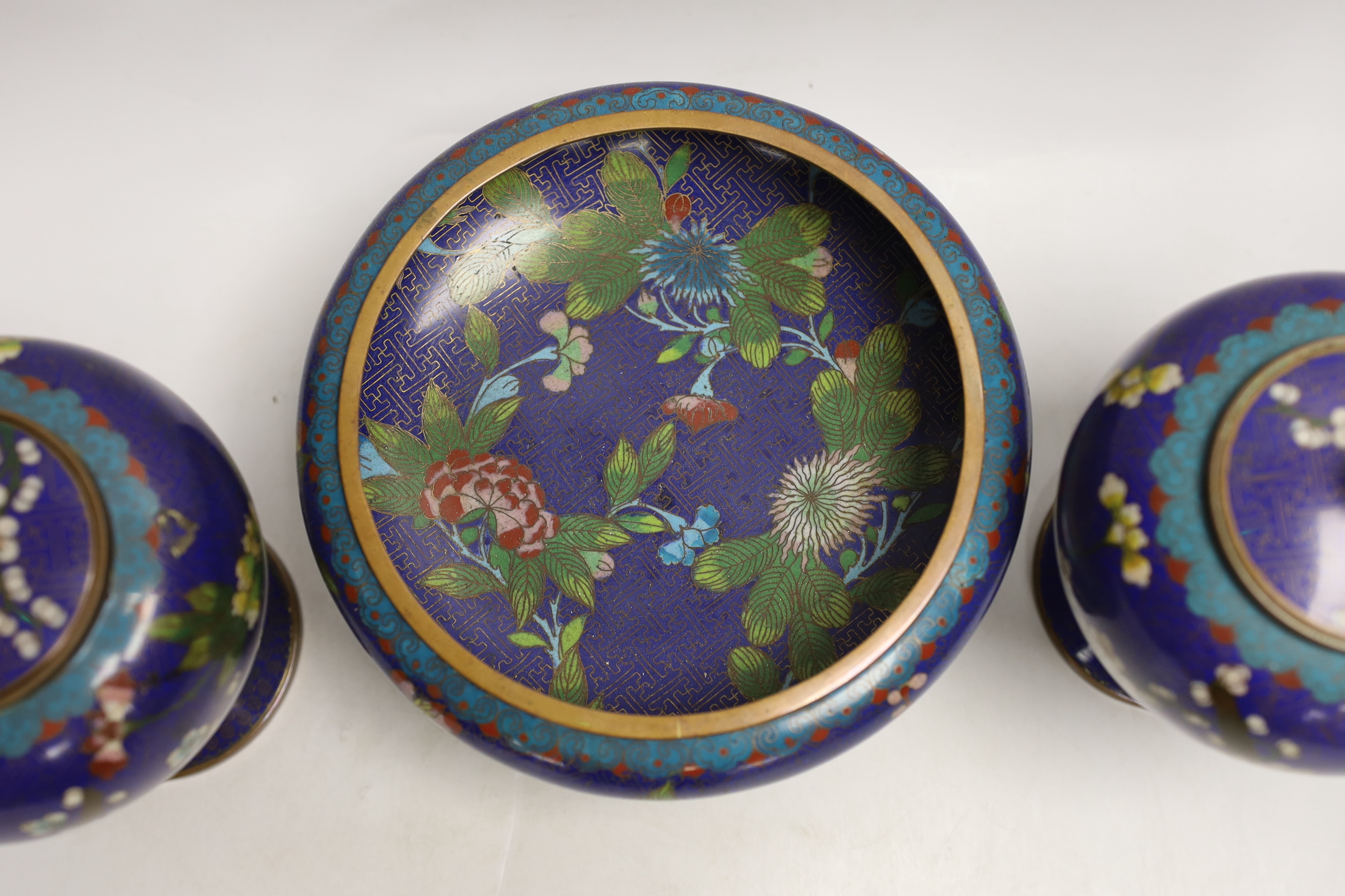 A pair of early 20th century Chinese cloisonné enamel jars and covers, together with a similar bowl and wood stand, largest 20cm high